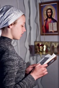 Young orthodox woman praying at icons